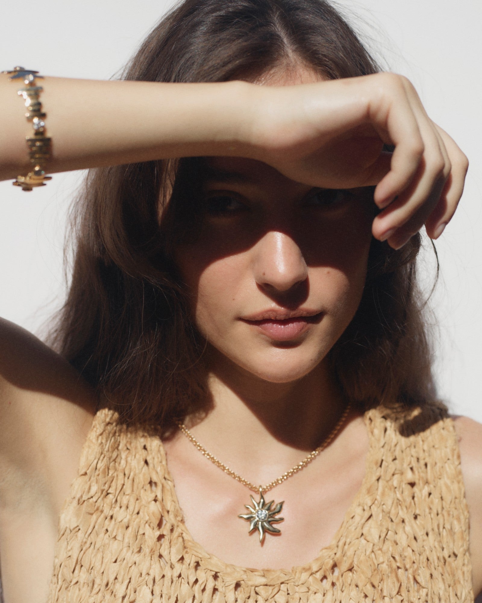 Model wearing the Sun pendant and a gold bracelet